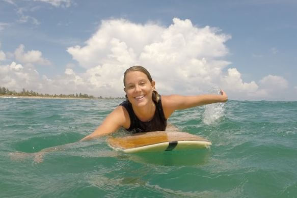 Happy surfer in the water paddling towards the camera